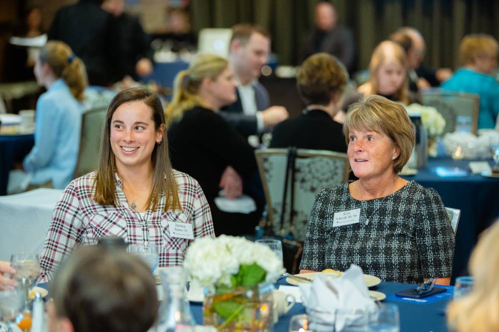 Kim Schmidt sitting with a student at Scholarship Dinner 2019